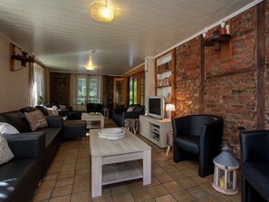 A living room with a sofa, a coffee table, a TV, and a brick wall.