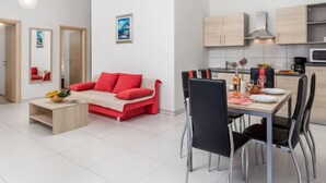 Eine moderne Wohnung mit einem roten Sofa, einem Esstisch und Stühlen. Sie verfügt über eine Küche mit Schränken und einer Mikrowelle.