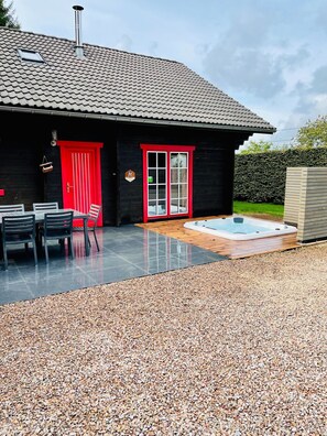 A modern house with a tiled roof, a red door, and a hot tub in the backyard. - Chalet in Ardennes With Sauna & Garden (Waimes)