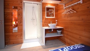 A wooden cabin bathroom with a shower, sink, mirror, and hanging clothes rack. - Chalet in Ardennes With Sauna & Garden (Waimes)