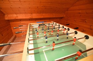 A foosball table in a wooden room with a sloped ceiling. - Chalet in Ardennes With Sauna & Garden (Waimes)