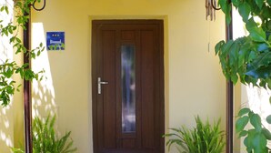 A yellow building with a brown door, potted plants, and a sign indicating a 3-star rating. - Comfortable Apartment Near the sea (Medulin)