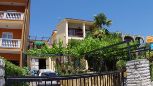 A residential building with a balcony, a car parked in front, and a sign indicating a boutique hotel. - Comfortable Apartment Near the sea (Medulin)
