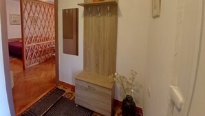 A hallway with a wooden door, a mirror, a shelf with a potted plant, and a vase with flowers. - Comfortable Apartment Near the sea (Medulin)