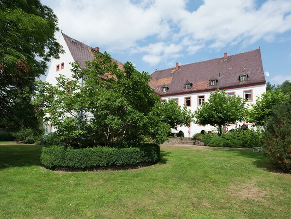 A large, white building with a red-tiled roof, surrounded by well-maintained lawns and trees. - Studio in Saxony Near Dubener Heide (Arzberg)