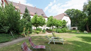 A garden with outdoor seating and a building with a red-tiled roof.