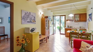 Un salón espacioso con un sofá rojo, una mesa de comedor de madera y una zona de cocina con armarios de madera y un salpicadero de azulejos.