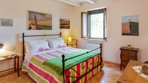 Un dormitorio con una cama, una mesita de noche, una mesa y un ventanal.