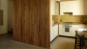 A modern kitchen with wooden beams, white cabinets, and a built-in oven. - Modern Accommodation, Just Renovated, Private Garden, Wifi, Near Treviso (Volpago del Montello)