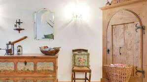 Quarto com cômoda de madeira, uma cadeira, cesta de vime, armário de madeira e um espelho na parede.