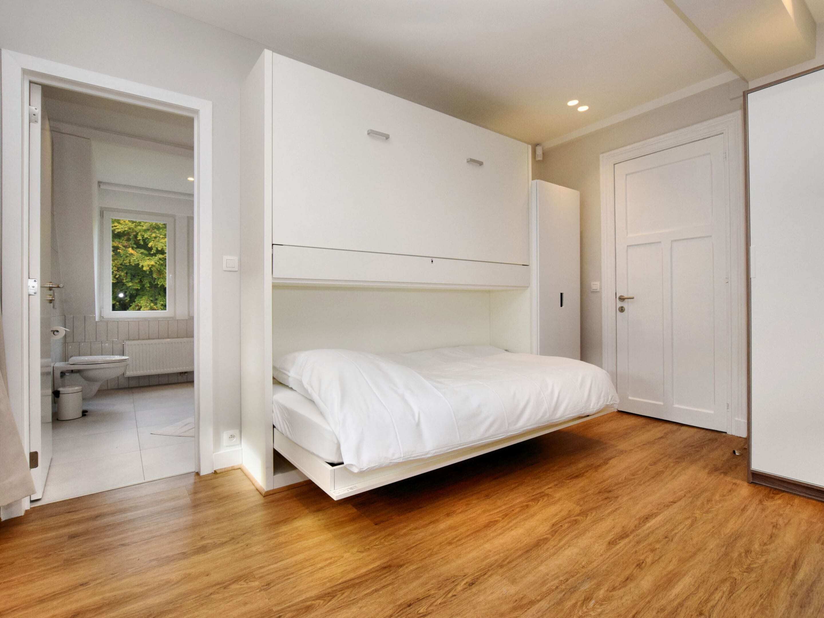 Una camera da letto con un letto a scomparsa, una finestra e una porta.
