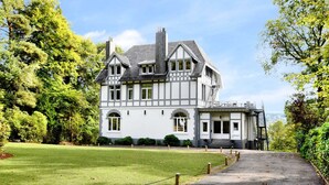 A large, two-story building with a symmetrical facade, multiple windows, and a prominent staircase leading to the entrance. - Opulent Holiday Home in Spa with Sauna, Hot Tub, Playroom (Spa)