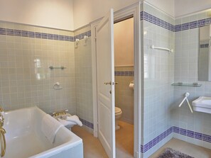 A bathroom with a bathtub, toilet, and shower area.