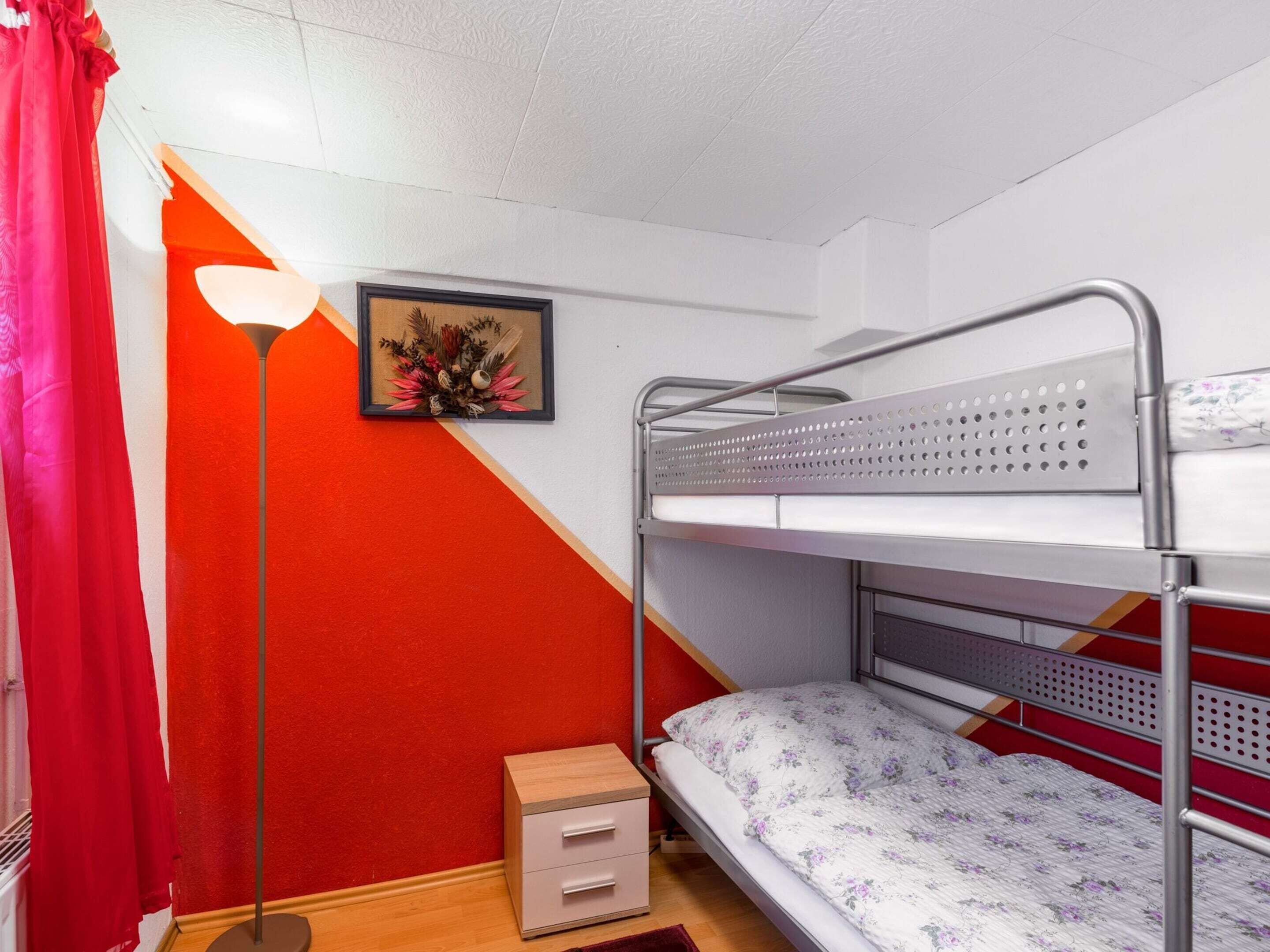 A bunk bed room with a small bedside table, a lamp, and a framed picture on the wall.