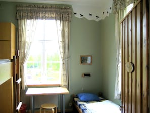 Una habitación pequeña y sencilla con cama, escritorio y ventana.