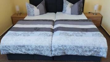 Ein Doppelbett mit schwarzem Kopfteil, zwei Nachttischen und einem gemusterten Bettüberwurf.