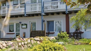 A two-story building with a balcony, a garden with rocks and plants, and a door marked with the number 11. - Apartment With Terrace in Rerik, Germany (Rerik)