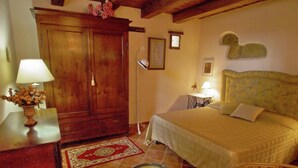 Une chambre à coucher avec un lit, une armoire en bois, une petite table avec une lampe et une chaise.