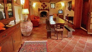 Un salon chaleureux avec une cheminée, un téléviseur et un coin repas comprenant une banquette et des chaises.