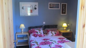 A bedroom with a bed, two bedside tables, a nightstand, a lamp, and a wall with framed pictures. - Spacious Chalet with Fruit Trees near Beach in Messinia (Messini)