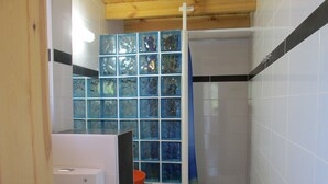 A bathroom with a shower area, a white toilet, and a blue glass partition. - Spacious Chalet with Fruit Trees near Beach in Messinia (Messini)