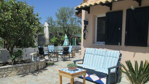 A patio with a sofa, chairs, and a table with a plant. - Spacious Chalet with Fruit Trees near Beach in Messinia (Messini)