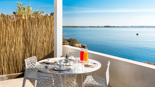 Ein Tisch für zwei mit Blick auf ein ruhiges Meer und eine entfernte Küste.