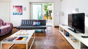 Ein modernes Wohnzimmer mit Sofa, Couchtisch, Fernseher und Bücherregal.