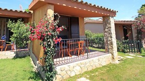 Una casa con patio, muros de piedra y un jardín con flores rojas.