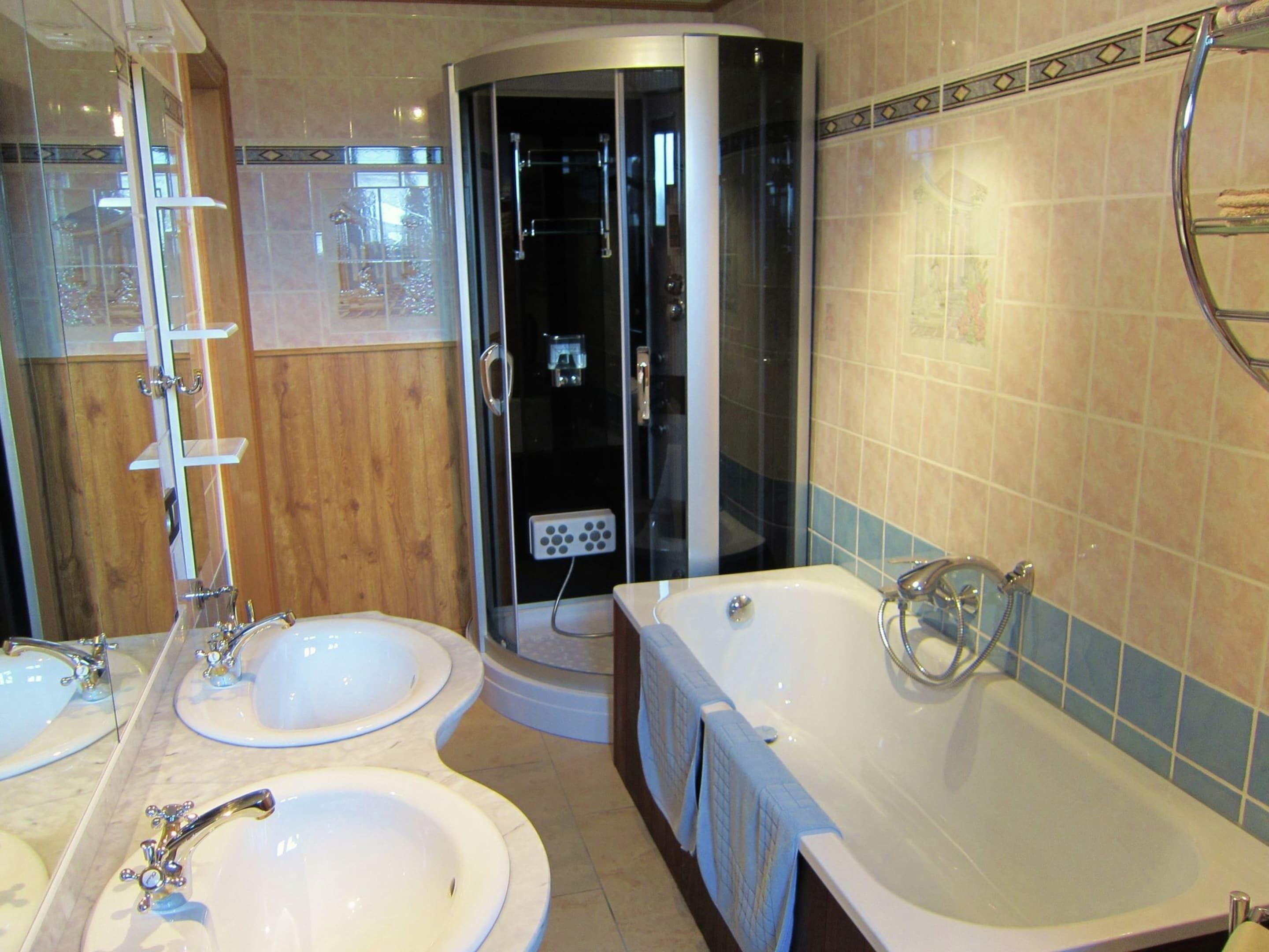 A bathroom with two sinks, a bathtub, and a glass-enclosed shower.