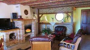 Un salon chaleureux avec une cheminée en briques, des meubles en cuir et un téléviseur.
