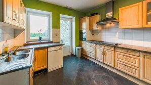 A modern kitchen with wooden cabinets, a dishwasher, a window with a view, and a stone backsplash. - Rustic Estate With Sauna (Nassogne)