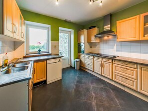 A modern kitchen with wooden cabinets, a dishwasher, a window with a view, and a stone backsplash. - Rustic Estate With Sauna (Nassogne)