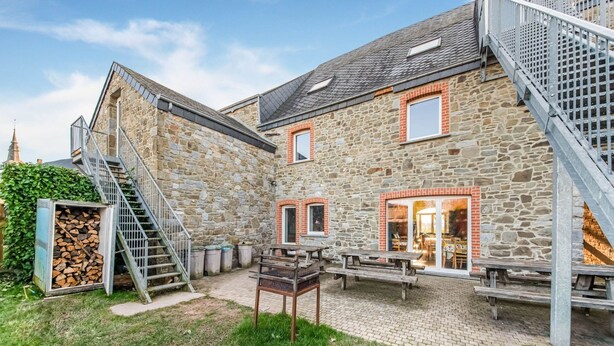 A stone building with a staircase, outdoor seating, and a pile of firewood. - Rustic Estate With Sauna (Nassogne)