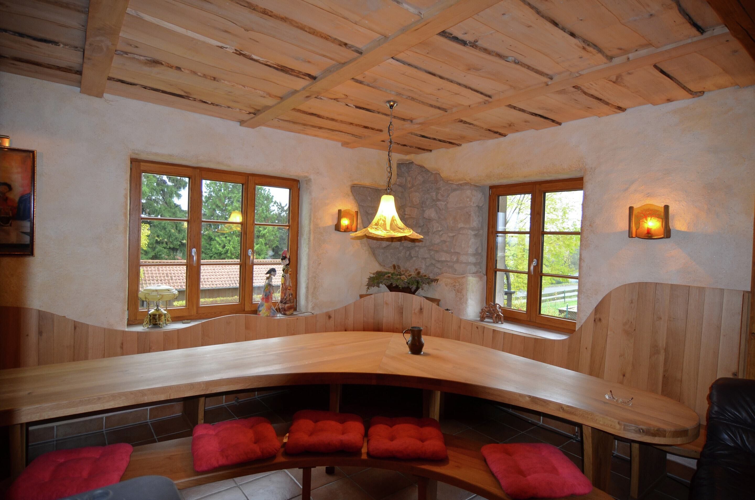 A wooden bench with red cushions, a stone wall, and a hanging light fixture.
