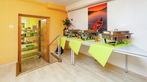 A dining area with buffet tables covered in green tablecloths, a wooden staircase, and a painting of a boat on water. - Dog-friendly Holiday Home in Hesse With Garden (Bad Zwesten)