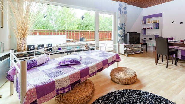 A modern bedroom with a bed, bedside tables, a TV, and a dining area with chairs and a table. - Dog-friendly Holiday Home in Hesse With Garden (Bad Zwesten)