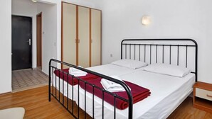 Un dormitorio con cama, armario, mesita de noche y lámpara de pared.