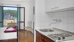 Cocina compacta con lavamanos, estufa y comedor con mesa y sillas.