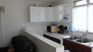 A compact kitchen with white cabinets, a toaster, and a sink. - Charming T2 '' Le Colibri '' garden floor with flowers and all comforts in Ste Anne Wifi (STE ANNE)