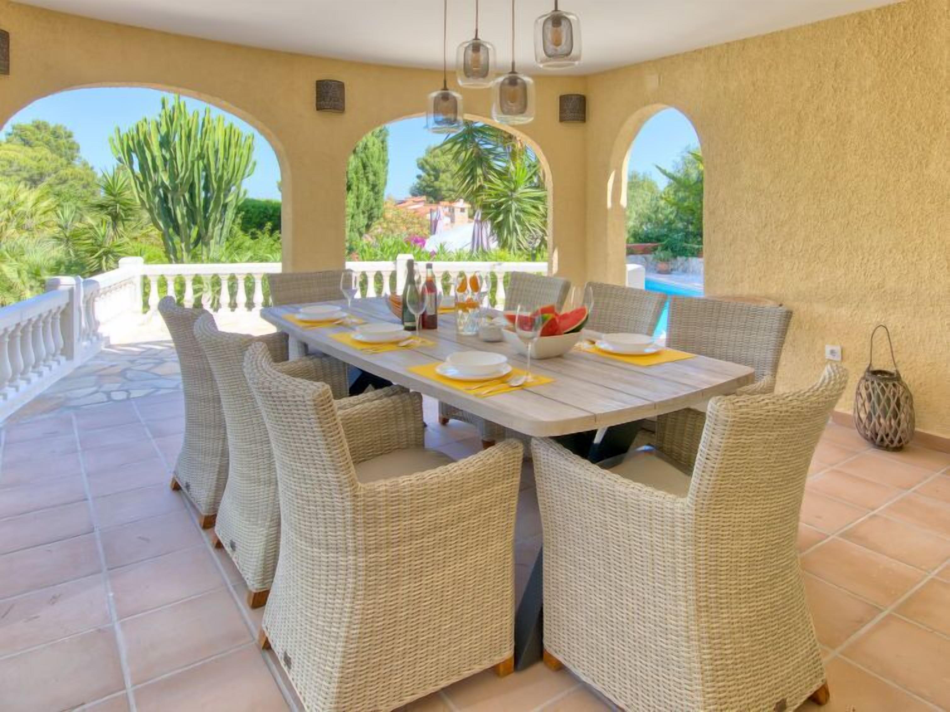 Un'area pranzo all'aperto coperta con sedie in vimini e un tavolo apparecchiato per quattro persone.