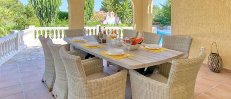 Un'area pranzo all'aperto coperta con sedie in vimini e un tavolo apparecchiato per quattro persone.