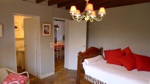Ein Schlafzimmer mit einem hölzernen Bett, roten Kissen, einer Chandelüster und einem durch eine offene Tür einsehbaren Badezimmer.