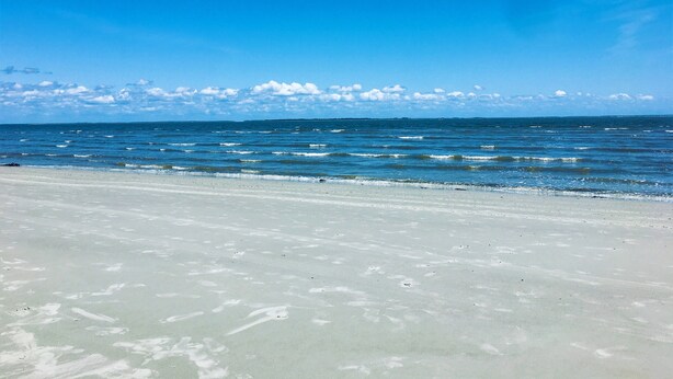 A beach with clear skies and calm waters. - Golf Cart, River and Marsh Views, Oceanfront Community, Beautiful Sunsets (St Helena Island)