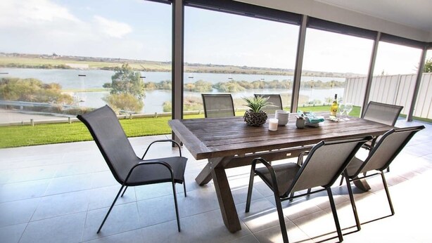 A dining area with a large table and chairs, overlooking a lake. - 'Serenity' and sweeping Murray River views (Tailem Bend)