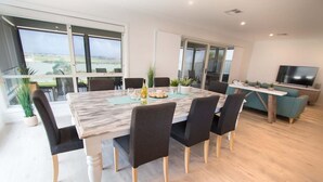 A modern dining area with a marble table, black chairs, and a view of a body of water through large windows. - 'Serenity' and sweeping Murray River views (Tailem Bend)