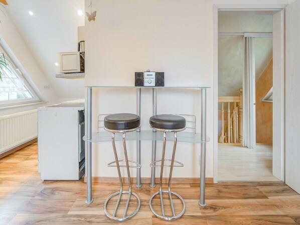 A modern kitchen with a glass-top table, two stools, and a radio. - Apartment in Schonow in Berlin/brandenburg (Bernau bei Berlin)