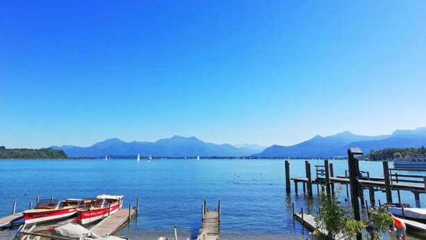 Un lac où des bateaux sont amarrés à un quai en bois, le tout étant entouré de montagnes.