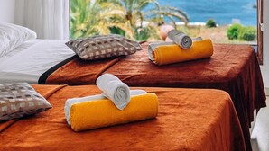 Una habitación de hotel con dos camas, un ventanal con vista al mar y una cortina.