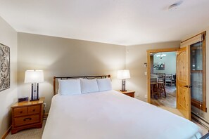 Relax in a spacious room with a large bed, bedside tables, and a door leading to a dining area.